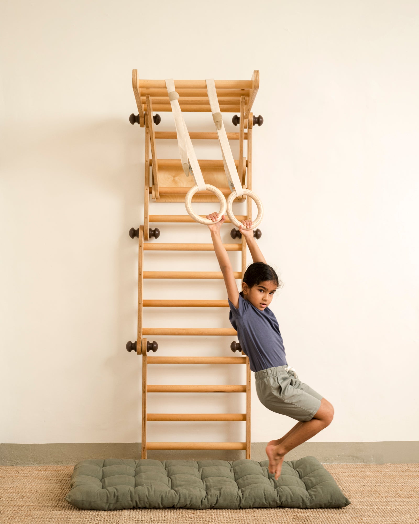 Keya playing on the transformable Pikler jungle gym with gymnastics rings