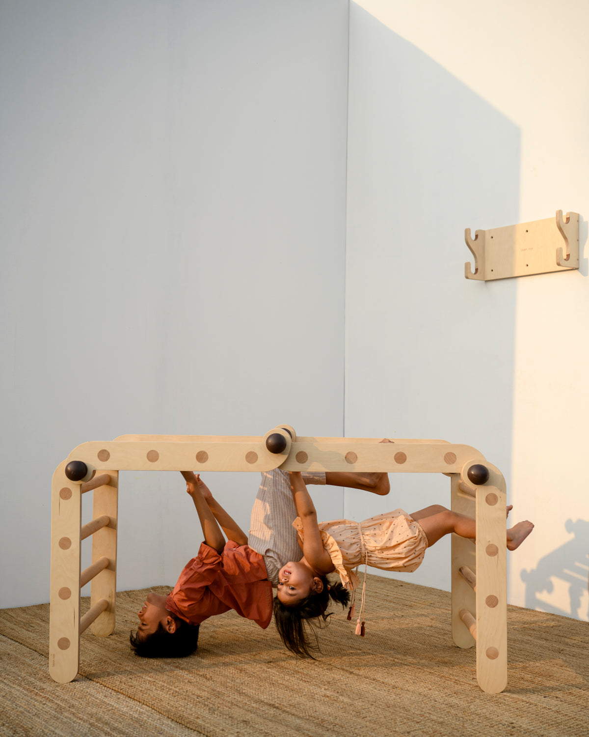 kids hanging upside down on transformable pikler jungle gym in bridge position