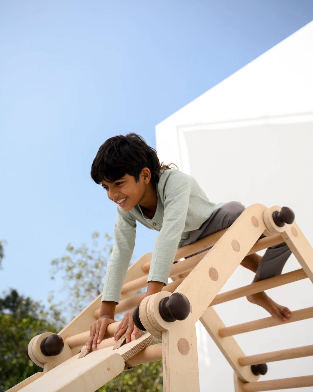 Child playing on the transformable Pikler jungle gym